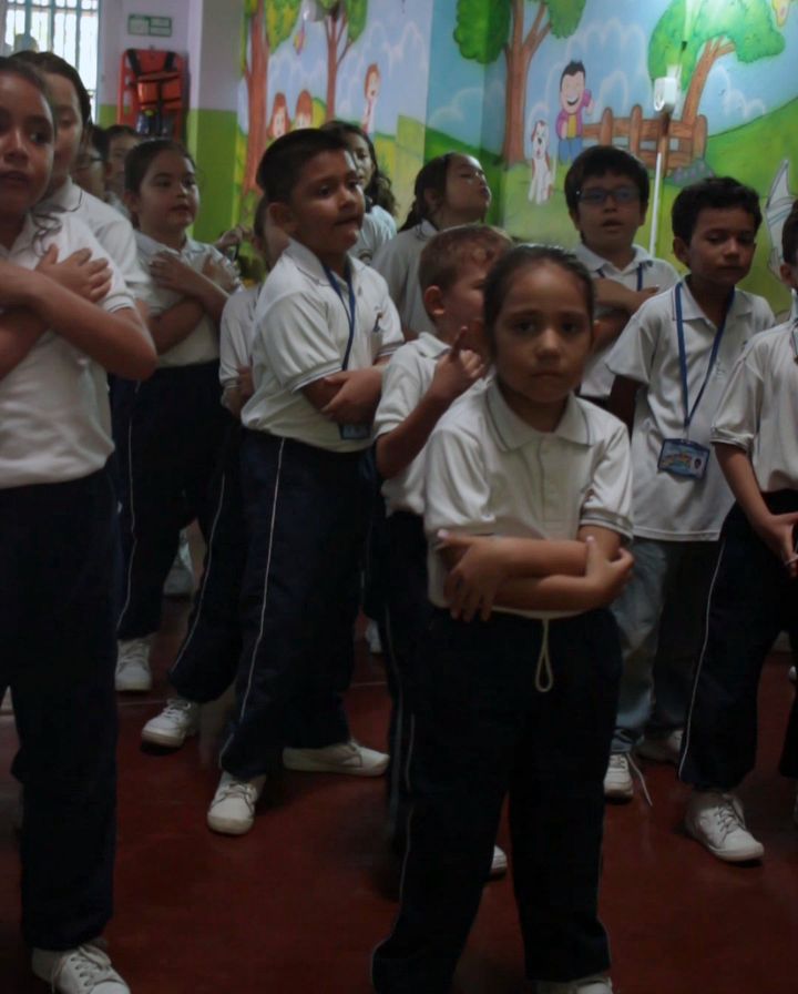 Estudiantes en el salón múltiple frente al mural del colegio