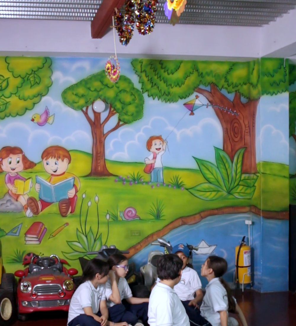Niños jugando en el salón múltiple del colegio, frente al mural pintado